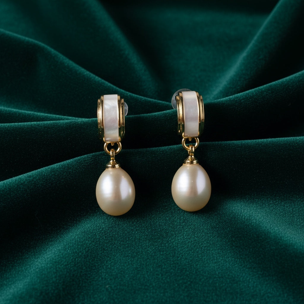 Charmluna teardrop pearl drop earrings featuring gold-tone hoops with cream inlay on dark green velvet fabric.