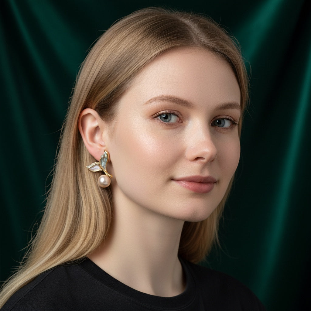 Charmluna wing pearl stud earrings with crystal accents worn by a woman against a dark green background