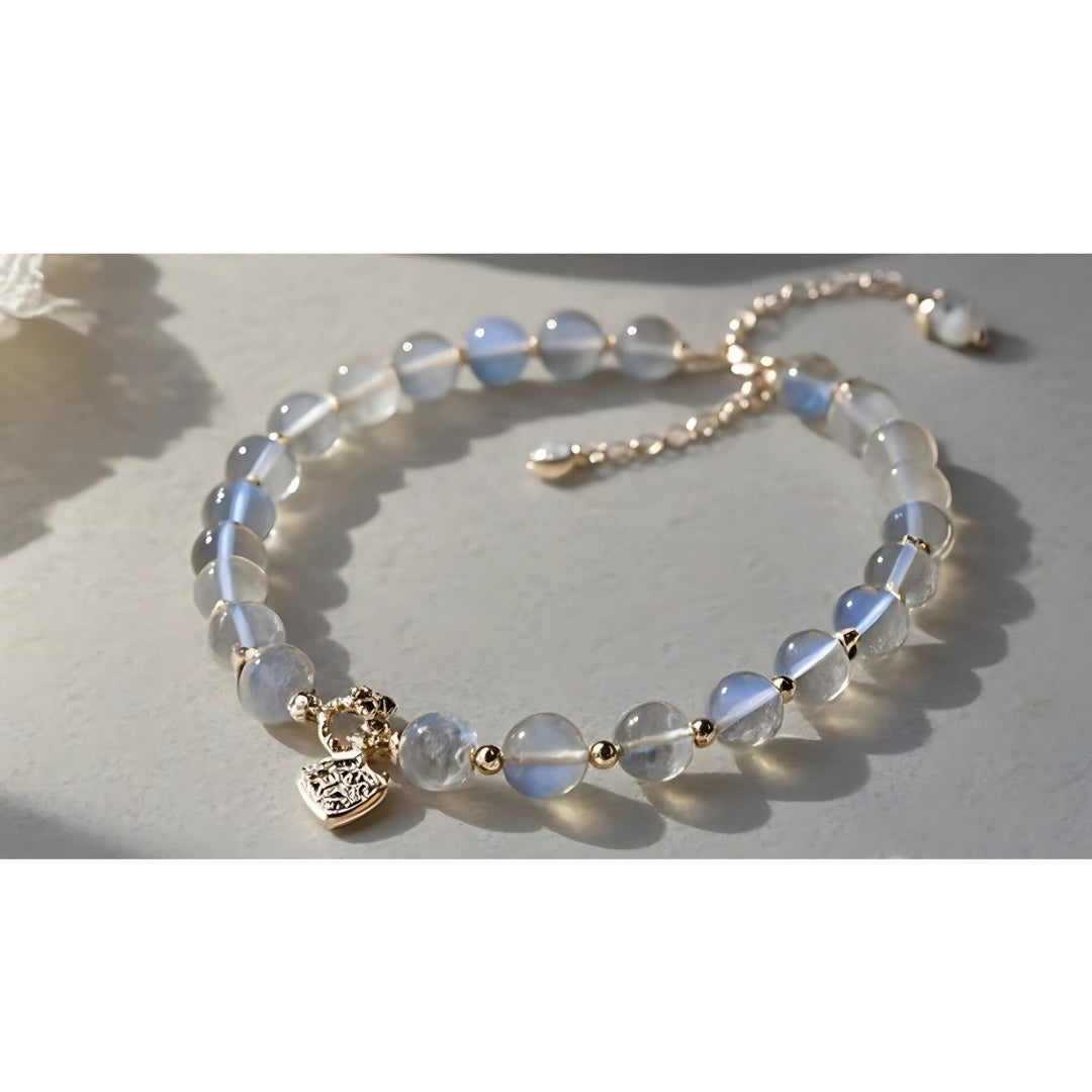 Charmluna moonstone beaded bracelet with gold heart charm and adjustable extender chain on a neutral surface.