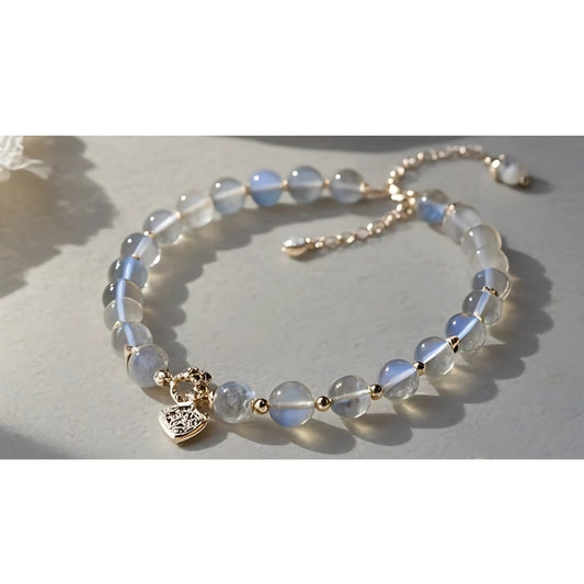 Charmluna moonstone beaded bracelet with gold heart charm and adjustable extender chain on a neutral surface.