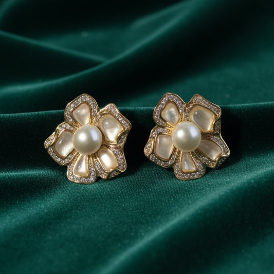 Charmluna mother of pearl blossom stud earrings with crystal trim and central pearl accents on green velvet.
