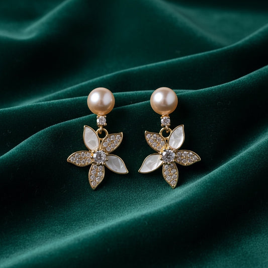 Charmluna peach pearl stud earrings with mother of pearl flower drops and crystal accents on green velvet.