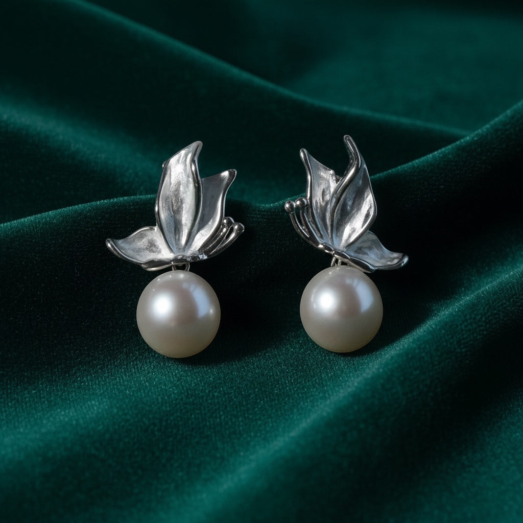 Charmluna silver leaf stud earrings featuring luminous round pearls on a dark green velvet background.