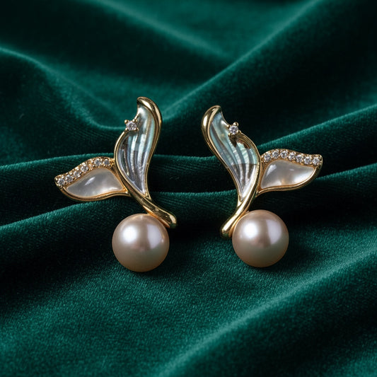 Charmluna wing-shaped mother of pearl stud earrings with crystal accents and round pearls on green velvet.